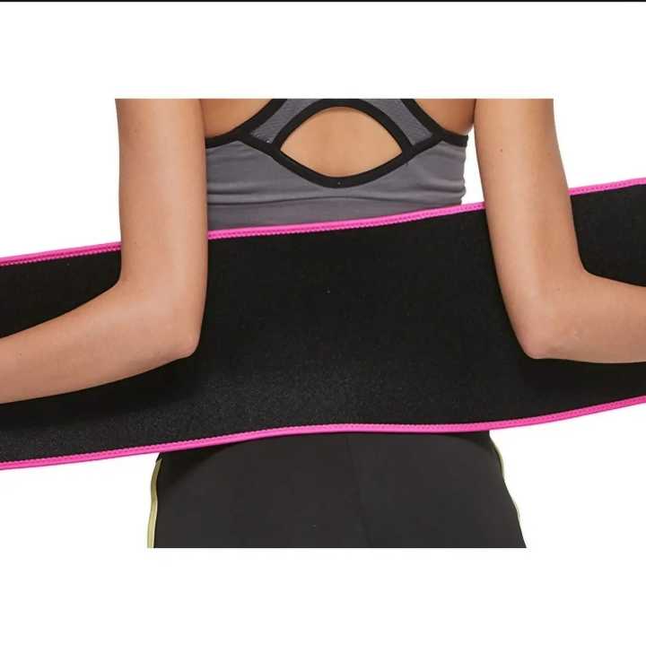 Woman holding waist trimmer belt open showing wide wrap-around band with pink trim
